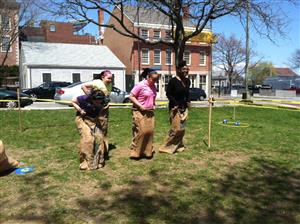 A lively scene of people playing a sack race, capturing a joyful moment in nature.