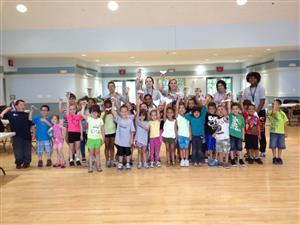 A cheerful group of children and adults smiling together for a photo, capturing a joyful moment.