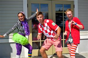 Three people in colorful costumes smiling and posing together for a fun photo.