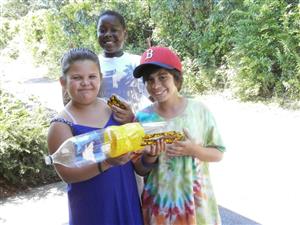 Three kids display a project, showcasing their excitement during a fun day.