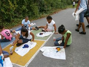 A group of children sitting on the ground, happily tie-dying shirts together.